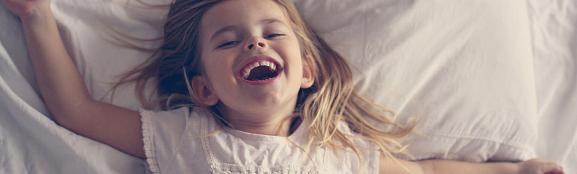 Niña feliz acostada en la cama