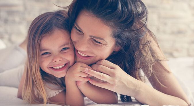 Madre e hija abrazadas en la cama